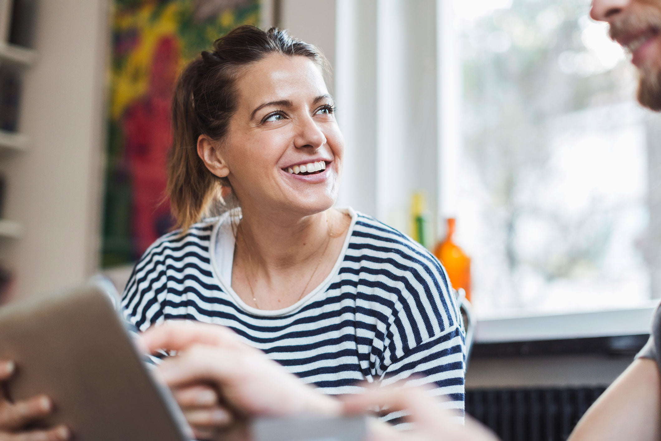 Kvinne med stripete genser som snakker med man med ipad
