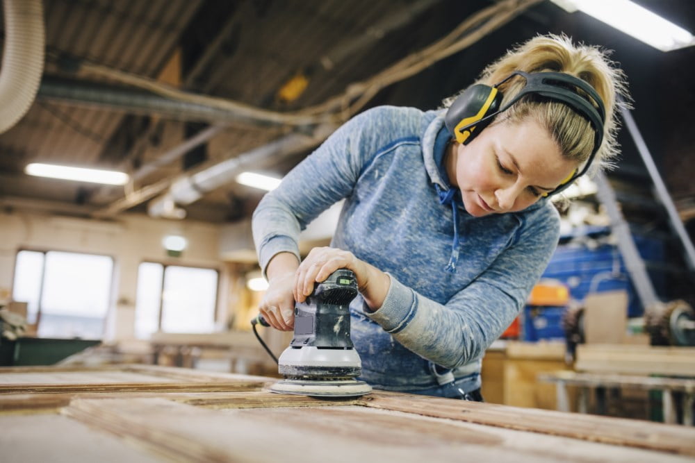 Kvinnelig snekker sliper en planke