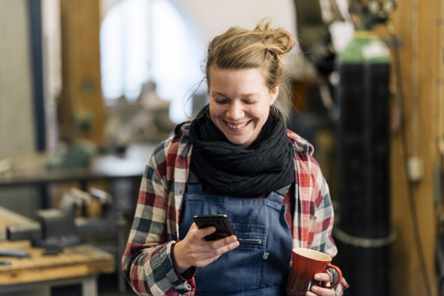 Dame i arbeidklær sjekker mobilen